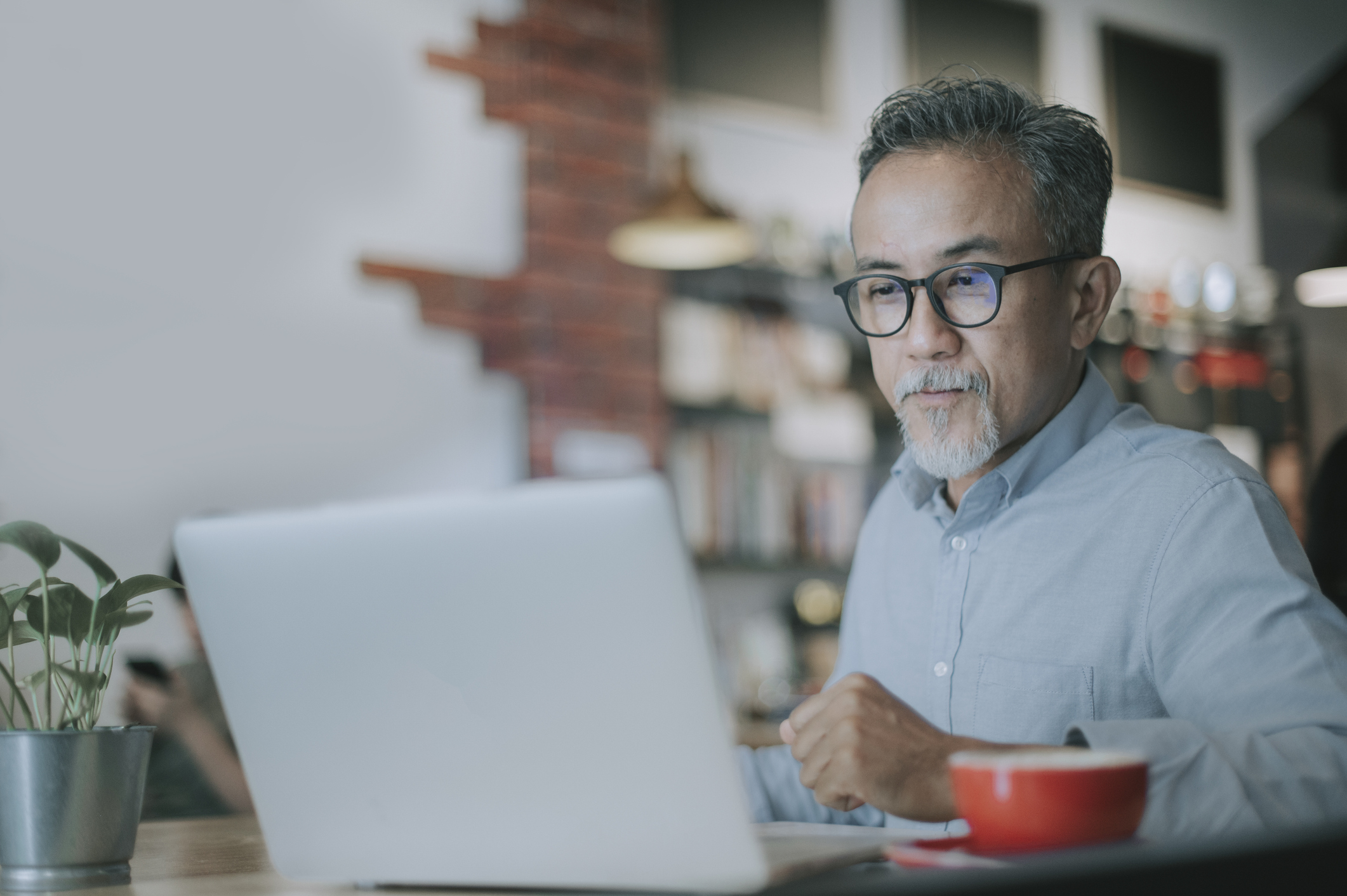 an asian chinese senior man having discussion with his colleague via online virtual meeting in a cafe an asian chinese senior man having discussion with his colleague via online virtual meeting in a cafe